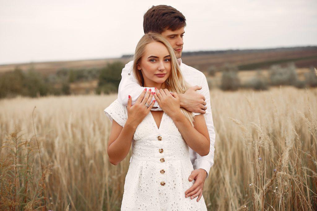 Cute couple in a field. Lady in a white dress. Guy in a white shirt