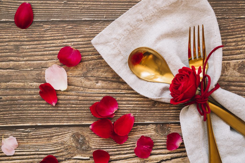 spoon-fork-with-red-flower-napkin-near-petals